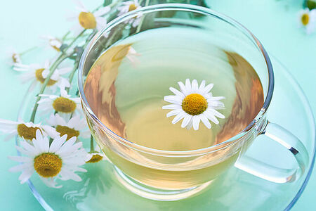 glass cup with decoction of chamomile and flowers