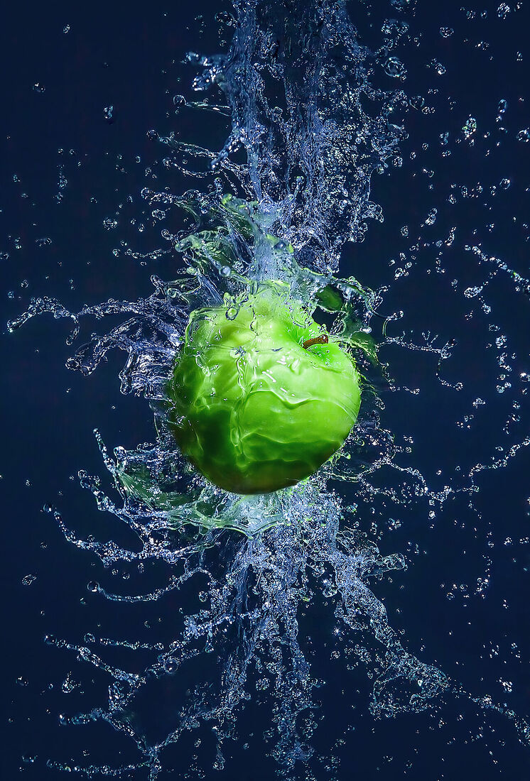 Ripe and juicy apple in water splashes